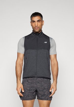 Chaleco negro y gris con cremallera, con un alto cuello, material ligero y dos bolsillos laterales, usado sobre una camiseta gris de manga corta.