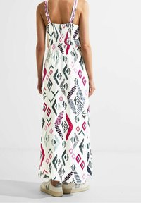 Robe maxi avec bretelles réglables, base blanche et motif géométrique multicolore en rose, vert et noir. Tissu léger, corsage ajusté.