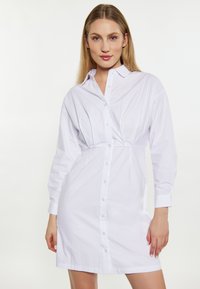 Weißes Hemdkleid mit Knopfverschluss, langen Ärmeln und einer taillierten Taille mit leichter Raffung vorne. Aus glatt gewebter Baumwolle.