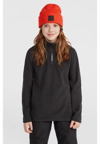 Pullover in pile nero con collo a mezza zip e dettaglio del logo. Indossato con un berretto arancione brillante. Tessuto liscio, vestibilità comoda.