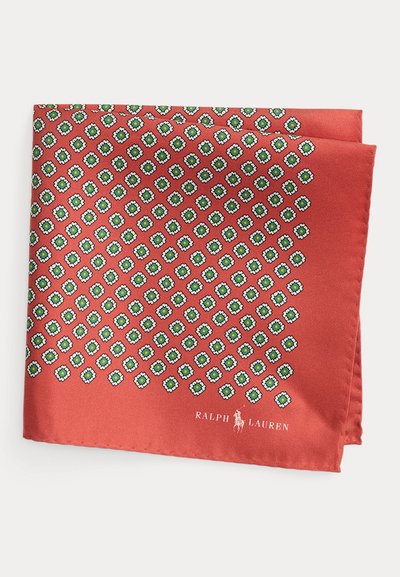 Μεταξωτό φουλάρι σε κοραλί χρώμα με γεωμετρικό σχέδιο από πράσινα και άσπρα διαμάντια. Ολοκληρώνεται με λογότυπο στην κάτω γωνία, με απαλή υφή.