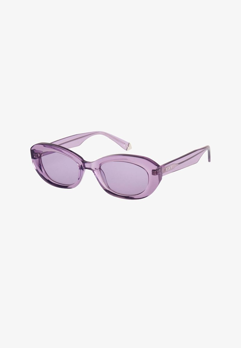 Lunettes de soleil ovales translucides violettes avec montures légèrement courbées et verres teintés, dotées de branches fines et d'un petit logo de marque sur le côté.
