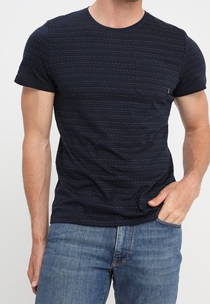 T-shirt à manches courtes bleu marine avec un motif rayé texturé et une poche poitrine. Confectionné en mélange de coton, assorti à un jean en denim bleu.