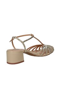 Sandalo beige con tacco basso a blocco, cinturino a T e decorazioni argentate scintillanti sulle fasce e nell'area delle dita.