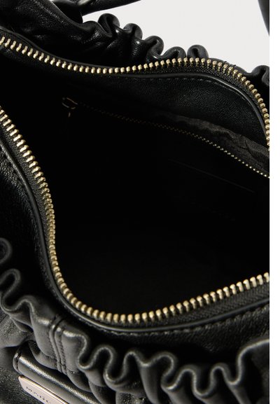 Μαύρη δερμάτινη τσάντα με χρυσό φερμουάρ ανοικτή μερικώς, αποκαλύπτοντας το σκούρο εσωτερικό και συγκεντρωμένες δερμάτινες λεπτομέρειες γύρω από την επάνω άκρη.