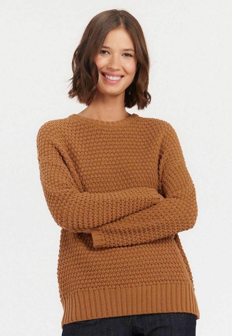Pull en tricot marron avec un motif texturé, encolure ronde et poignets et ourlet côtelés ; coupe décontractée. Porté avec un jean en denim foncé.