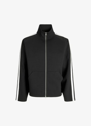 Mustakas lukuga jope kõrge kaelusega, millel on valged külgriided, kaks eesmist taskut ja pehme, tekstuuriga kangas.