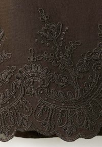 Tissu sombre avec une broderie florale noire complexe et un bord festonné.