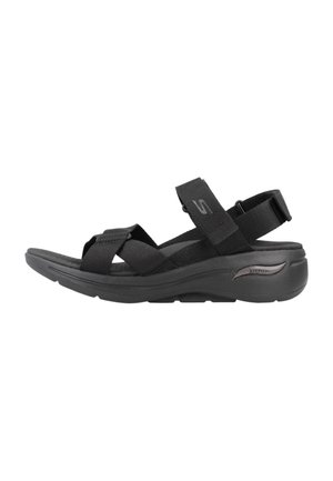 Sandalias deportivas negras con correas ajustables, plantilla acolchada y suela de goma flexible. Presenta un diseño aerodinámico y un branding mínimo.