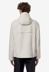 Giacca impermeabile beige chiaro con cappuccio, dotata di una ventola posteriore, maniche lunghe e un taglio dritto. Tessuto liscio, design minimale.