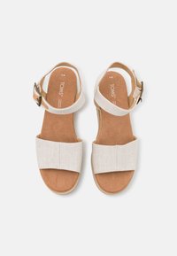 Beige stoffen sandalen met twee brede banden en een enkelgesp, met een zachte bruine voetbed en lichte platformzolen.
