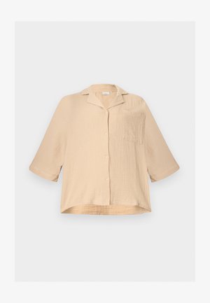 Μπεζ, άνετη, υφασμάτινη πουκάμισα με κουμπιά, με μανίκια μέχρι τον αγκώνα, μικρό γιακά και μια τσέπη στο στήθος, σε απλό φόντο.