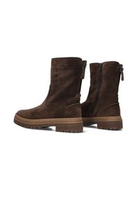Bottines en suede marron avec une semelle en caoutchouc plate, dotées d'une fermeture éclair sur le côté et de détails cousus le long des coutures.