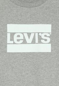 Tessuto grigio con logo Levi's bianco centrato, caratterizzato da lettere in grassetto tra due barre orizzontali bianche.