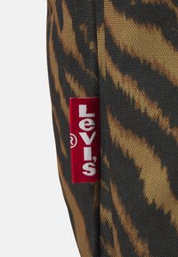 Borsa Levi's con motivo a strisce tigre in marrone e nero, con un'etichetta rossa prominente che mostra il nome del marchio in bianco.