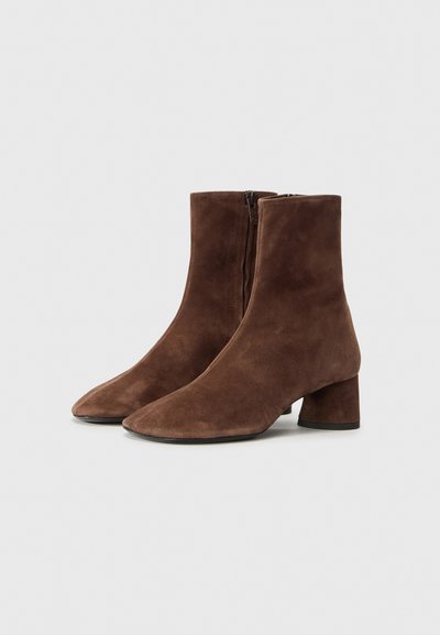 Botines de ante marrón hasta el tobillo con punta afilada, cremallera lateral y tacón cuadrado. Textura suave y diseño sin costuras.