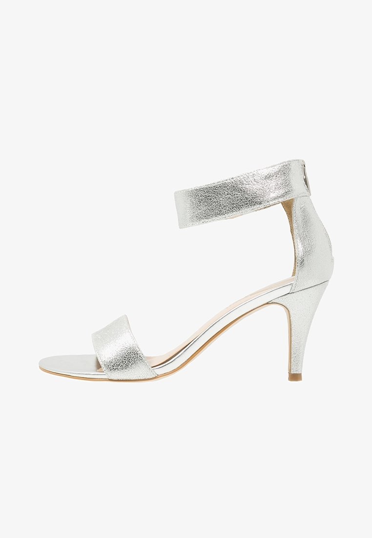 Sandale à talon haut métallique argenté avec bride à la cheville, bout ouvert et surface texturée. Talon stiletto au design élégant avec des accents minimalistes.
