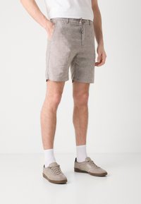 Light gray linen shorts with a drawstring waistband, side pockets, and a mid-thigh cut, paired with tan sneakers and white socks.