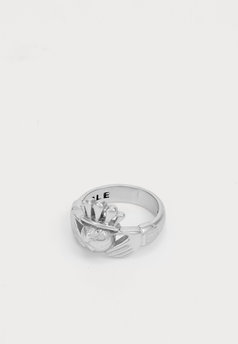 Anillo Claddagh de plata con manos sosteniendo un corazón coronado sobre un fondo blanco liso.