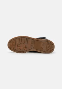 Podeszwa sneakersów Puma z brązowym gumowym spodem, posiadającym teksturowane wzory antypoślizgowe oraz wytłoczone logo, zaprojektowana z myślą o przyczepności i trwałości.