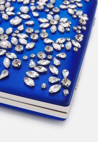 Blå satinklutch prydd med olika klara rhinestones, i olika former och storlekar, och ett silverfärgat spänne.