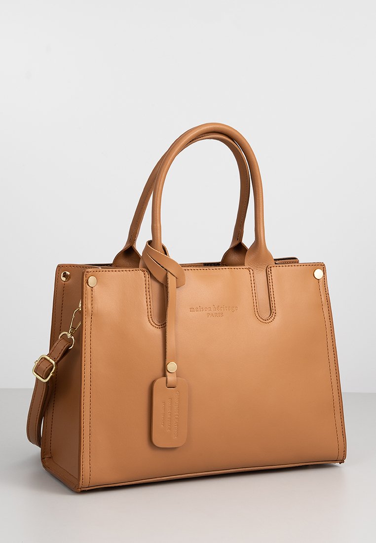 Tasche aus braunem Leder mit zwei oberen Griffen, abnehmbaren Schultergurt, goldfarbener Hardware und geprägtem Logo. Glatte Textur, strukturierte Form.