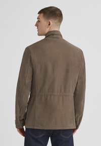 Braune Leinenjacke mit hohem Kragen, geknöpften Manschetten und lässiger Passform. Glatte Textur und feine Nahtdetails an der Taille.