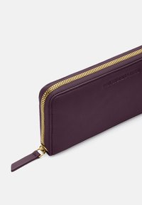 Purple leather wallet with a gold zipper. It features a flat design and embossed text on one side. Smooth texture and sleek appearance.