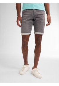 Shorts de mezclilla gris con dobladillos enrollados, que presentan una textura sutil y un diseño ajustado. Combinados con zapatillas blancas para un look casual.