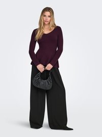 Bordo rebrasti top dugih rukava s V-izrezom, uparen s širokim crnim hlačama i teksturiranom crnom torbom. Minimalistički dizajn, mekani materijal.