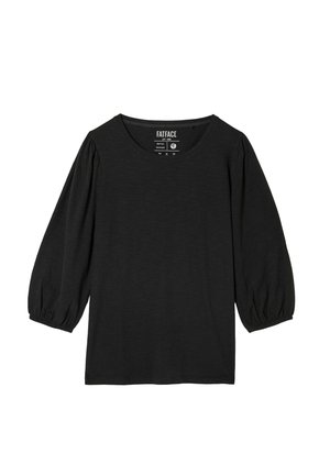 Haut noir à manches longues avec un col rond et des manches bouffantes froncées. Tissu doux et texturé avec une coupe décontractée. Étiquette visible au niveau du col.