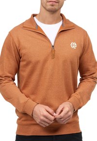 Orange sweatshirt med en kvart lynlås og et lille logo på brystet. Har struktureret stof og kontrasterende stribede detaljer i kraven.