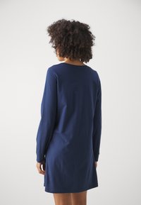Navy long-sleeve dress in cotton, semi-fitted design, round neckline, and mid-thigh length with side slits for ease of movement.