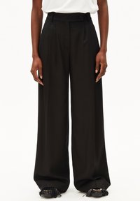 Schwarze, weit geschnittene Hose mit hoher Taille, Falten und einem Knopfverschluss. Aus glattem Stoff gefertigt und zeigt ein sauberes, minimalistisches Design.