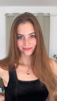 Πορτραίτο ενός ατόμου με μακριά, ίσια καστανά μαλλιά, που φοράει ένα μαύρο βελούδινο τοπ και ένα χρυσό κολιέ με κυκλικό μενταγιόν.