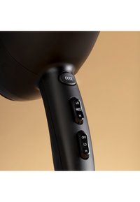 Czarna rączka suszarki do włosów z przyciskami sterującymi do ustawień zimny, wyłączony, niski, średni i wysoki; gładka tekstura z zaokrąglonym wzorem.