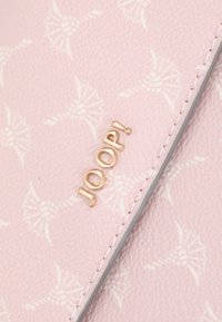 Pink material wallet with embossed floral pattern. Features gold logo "JOOP!" and contrasting gray edge stitching. Smooth texture.