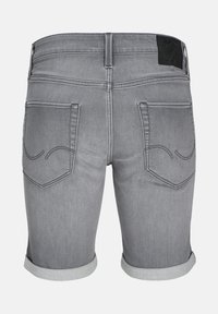 Short en denim gris avec ourlets roulés, deux poches arrière avec des motifs cousus et une étiquette de marque noire sur la ceinture.