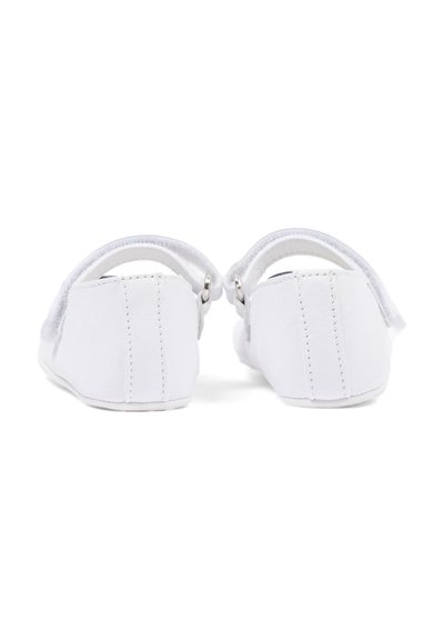 Chaussures blanches pour bébé avec brides à la cheville, vues de dos, montrant les détails de la couture et les petites boucles métalliques.