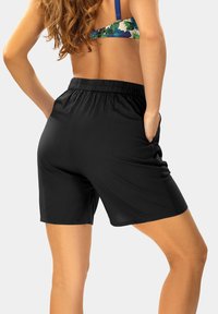 Czarne, teksturowane szorty z elastycznym pasem i bocznymi kieszeniami. Materiał jest lekki, co zapewnia wygodne dopasowanie.
