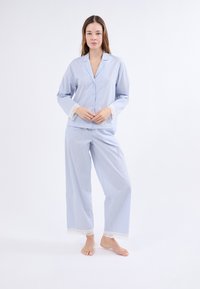 Pijamas de color azul claro que cuentan con una parte superior abotonada con mangas con encaje y pantalones sueltos a juego con detalles de encaje en el dobladillo.