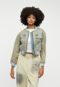 Kratka jeans jakna v svetlo modri barvi z rebrastimi manšeti in ovratnikom, z sprednjimi žepi in kontrastno modrim panelom po sredini.