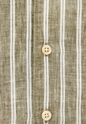 Tkanina w beżowo-białe pionowe paski z dwoma beżowymi guzikami z czterema dziurkami przyszytymi na środku.