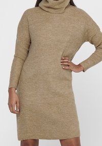 Abito a collo alto in maglia color marrone chiaro, caratterizzato da una vestibilità comoda, una texture a costine, maniche lunghe e un orlo che arriva sopra il ginocchio.