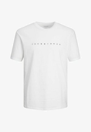 T-shirt bianca in cotone con logo stampato, abbinata a pantaloni felpati grigi chiari con nome del brand. Calzature: sneakers bianche. Outfit semplice e casual.