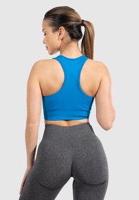 Top de tirantes cortos de color azul con diseño de espalda nadadora, combinado con leggins oscuros de cintura alta en gris. Textura delineada en ambas piezas.