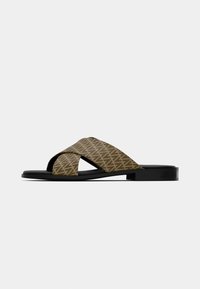 Brune mønstrede slip-ons med kryssremdesign, med en strukturert stoff-overdel og en svart flat såle.