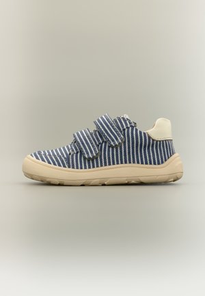 Kindersneaker met blauw-witte strepen, twee klittenbandsluitingen, beige zool en crème hielondersteuning, zijaanzicht op een neutrale achtergrond.