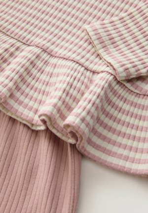 Pamut felső rózsaszín és tejszínszín kockás mintával, fodros szegéllyel és bordás textúrával. Rövid ujjú, diszkrét mandzsettával a végen.