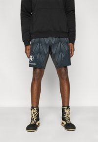 Μαύρο φούτερ με κουκούλα και μπροστινή τσέπη· γκρί σορτς με μοτίβο κυμάτων, λογότυπο και λεπτομέρειες στα πλάγια· μαύρα και χρυσά ψηλά αθλητικά παπούτσια.